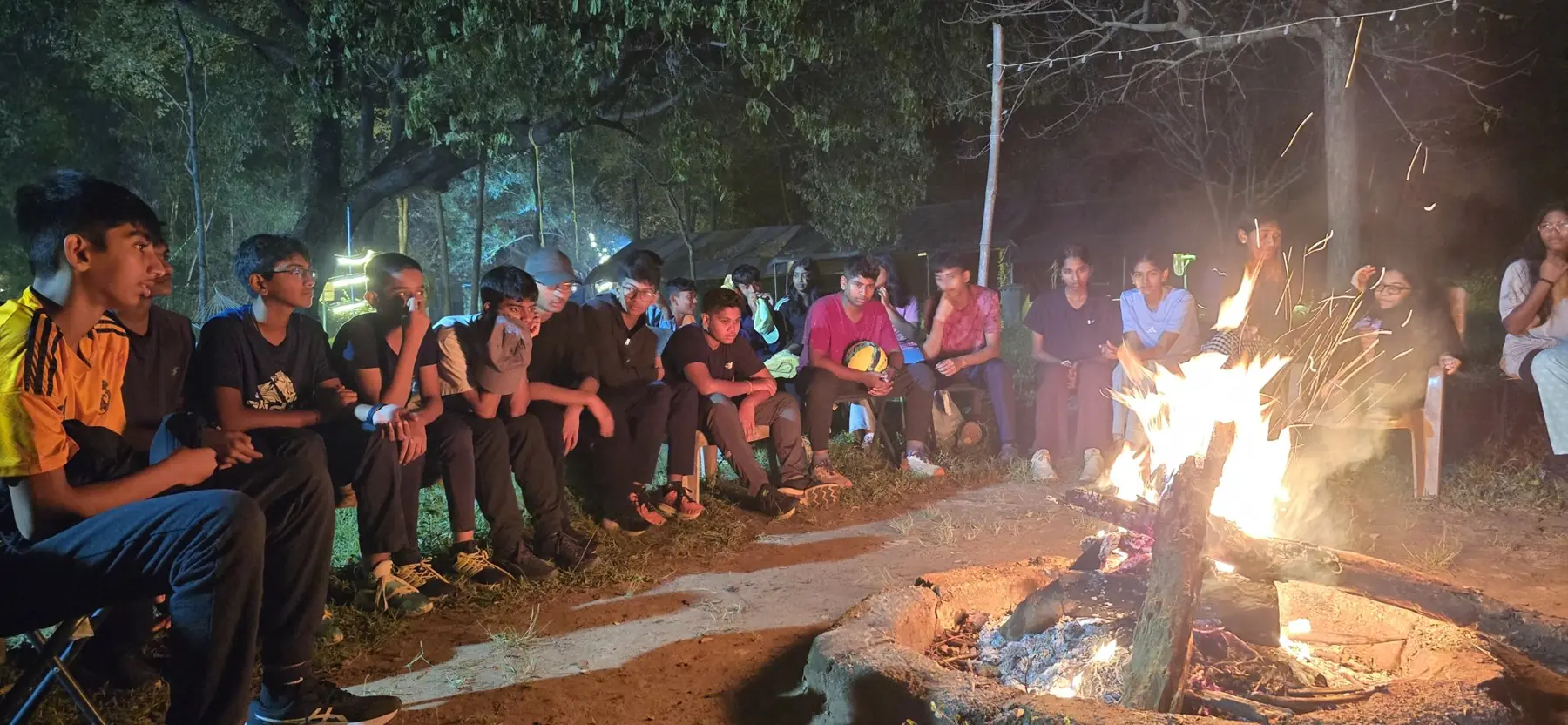 Students sitting around a campfire at night