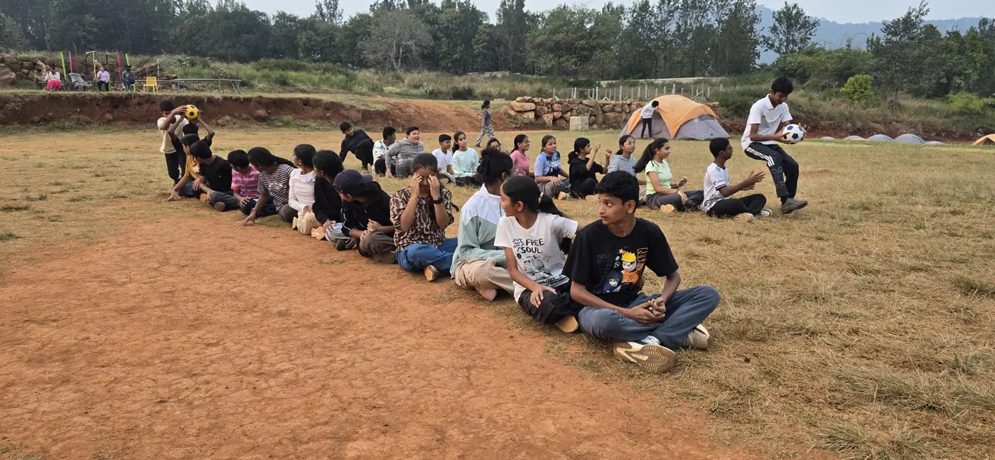 Students playing a seated game on the campsite field