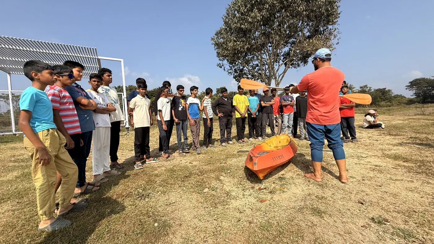 An instructor demonstrating paddling from a kayak to a line of students