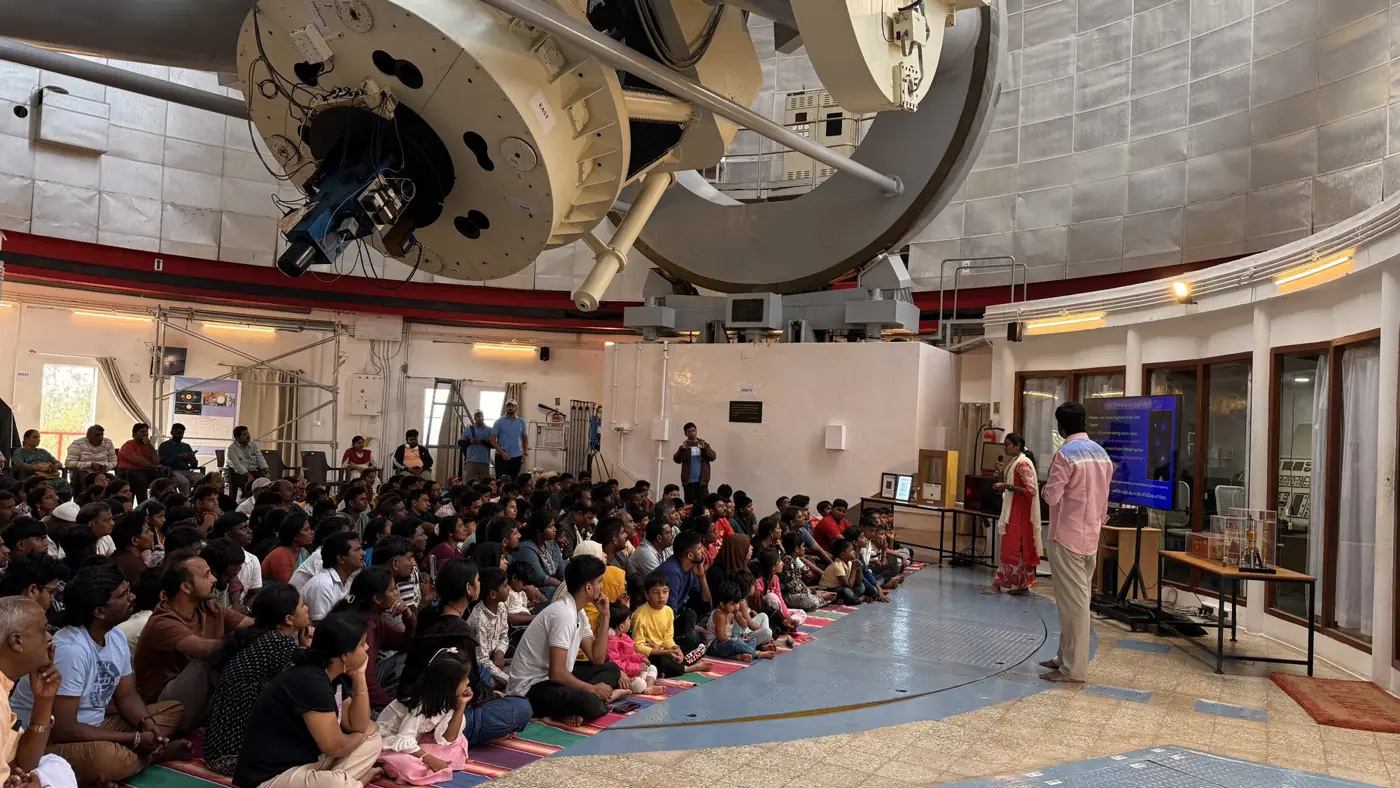Students seated beneath a large research telescope inside an observatory