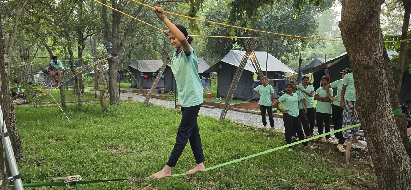 A student balancing on a slackline while classmates watch