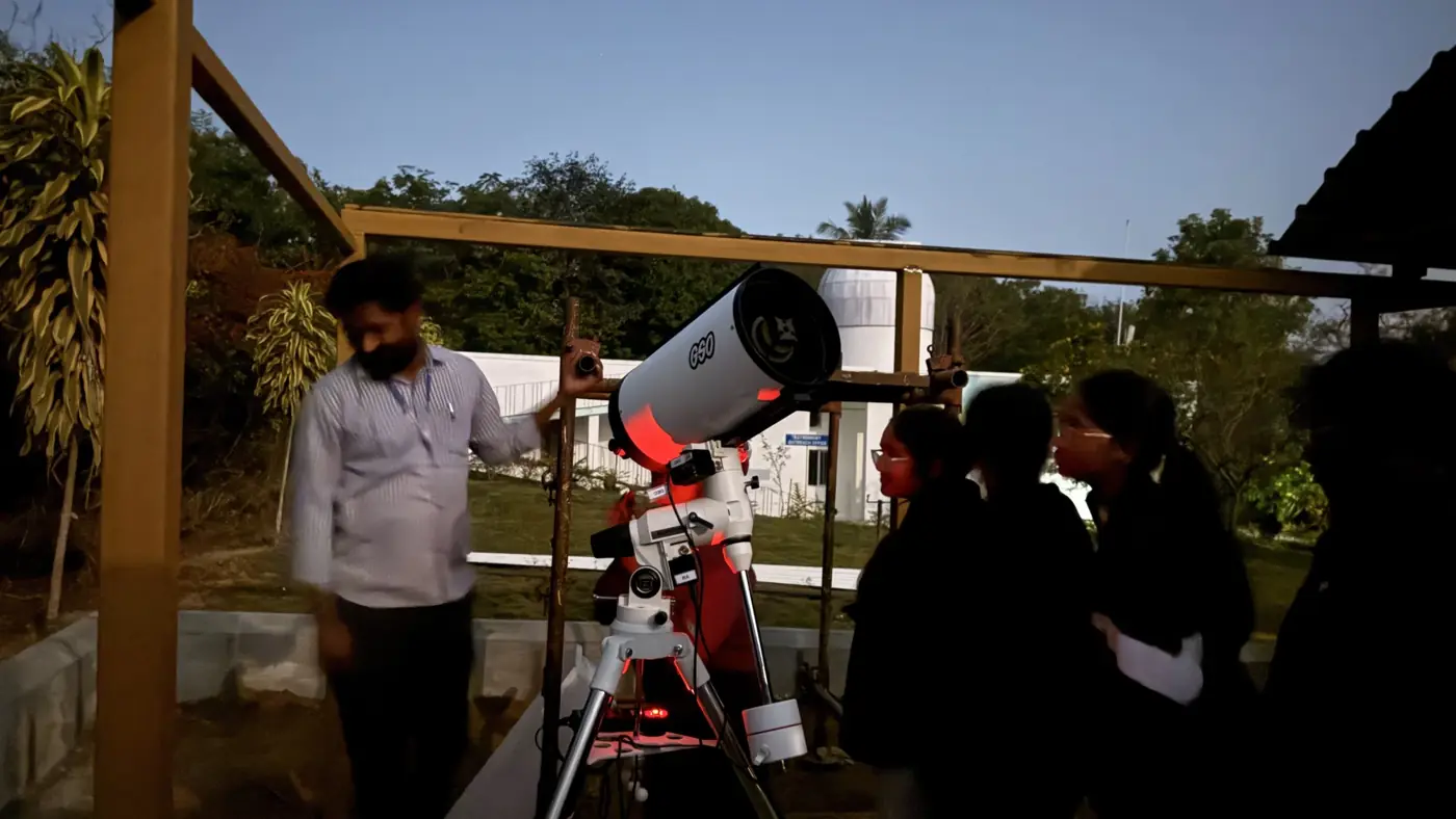 An instructor setting up a telescope for students at dusk
